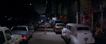 Movie still from “Rumble in the Bronx” (1995), directed by Stanley Tong – A man skateboarding in a parking lot at night; Wide shot, High angle