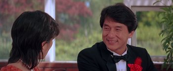 Movie still from “Rumble in the Bronx” (1995), directed by Stanley Tong – A man wearing a suit and bow tie smiling; Close Up shot, Over the shoulder angle