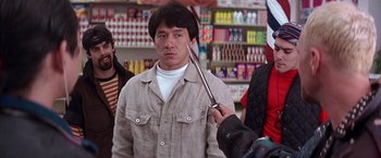 Movie still from “Rumble in the Bronx” (1995), directed by Stanley Tong – A man is holding a pair of scissors in his hand; Medium shot, Over the shoulder angle