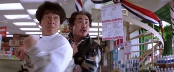 Movie still from “Rumble in the Bronx” (1995), directed by Stanley Tong – Two men standing next to each other in front of signs; Medium shot, Low angle