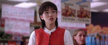 Movie still from “Rumble in the Bronx” (1995), directed by Stanley Tong – A young woman wearing glasses and a red vest; Close Up shot, Low angle