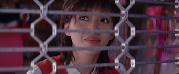 Movie still from “Rumble in the Bronx” (1995), directed by Stanley Tong – A woman looking through a metal fence; Close Up shot, Low angle