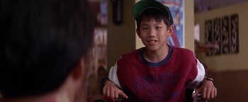 Movie still from “Rumble in the Bronx” (1995), directed by Stanley Tong – A young boy wearing a green hat and a red shirt; Close Up shot, Over the shoulder angle