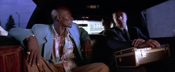 Movie still from “Rumble in the Bronx” (1995), directed by Stanley Tong – Two men sitting in the back seat of a car; Medium shot, Low angle