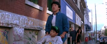 Movie still from “Rumble in the Bronx” (1995), directed by Stanley Tong – A man standing next to a young boy on a street; Medium shot, Over the shoulder angle