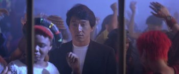 Movie still from “Rumble in the Bronx” (1995), directed by Stanley Tong – A man standing in a crowd of people in a room; Close Up shot, Over the shoulder angle