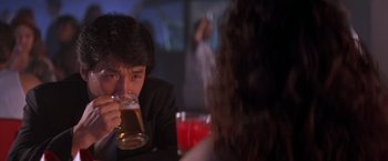 Movie still from “Rumble in the Bronx” (1995), directed by Stanley Tong – A man drinking a glass of beer at a table; Close Up shot, Over the shoulder angle