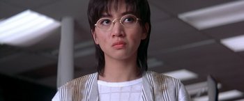 Movie still from “Rumble in the Bronx” (1995), directed by Stanley Tong – A woman wearing glasses and a white shirt looking to her left; Close Up shot, Low angle