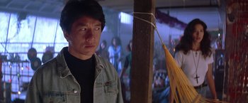 Movie still from “Rumble in the Bronx” (1995), directed by Stanley Tong – A man standing next to a wooden pole with an umbrella; Close Up shot, Over the shoulder angle