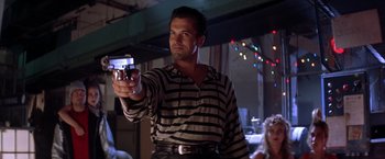 Movie still from “Rumble in the Bronx” (1995), directed by Stanley Tong – A man holding a cell phone in his hand; Medium shot, Low angle