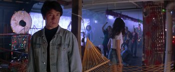 Movie still from “Rumble in the Bronx” (1995), directed by Stanley Tong – A man standing in front of a group of people; Medium shot, Over the shoulder angle
