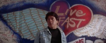 Movie still from “Rumble in the Bronx” (1995), directed by Stanley Tong – A man standing in front of a wall that has graffiti on it; Close Up shot, Low angle