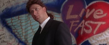 Movie still from “Rumble in the Bronx” (1995), directed by Stanley Tong – A man in a black suit and white shirt; Close Up shot, Low angle