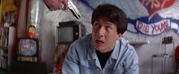 Movie still from “Rumble in the Bronx” (1995), directed by Stanley Tong – A man holding a gun up to his face; Close Up shot, Over the shoulder angle