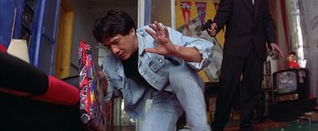 Movie still from “Rumble in the Bronx” (1995), directed by Stanley Tong – A man in a jean jacket is doing a trick; Medium shot, Low angle