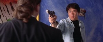 Movie still from “Rumble in the Bronx” (1995), directed by Stanley Tong – A man holding a gun in front of another man; Close Up shot, Over the shoulder angle