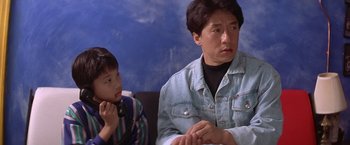 Movie still from “Rumble in the Bronx” (1995), directed by Stanley Tong – A woman and a boy sitting next to each other on a couch; Close Up shot, High angle