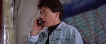 Movie still from “Rumble in the Bronx” (1995), directed by Stanley Tong – A man talking on a cell phone while wearing a jean jacket; Close Up shot, Low angle