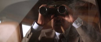 Movie still from “Rumble in the Bronx” (1995), directed by Stanley Tong – A man looking through a pair of binoculars at a cigarette; Extreme Close Up shot, Low angle