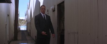 Movie still from “Rumble in the Bronx” (1995), directed by Stanley Tong – A man in a suit and tie standing in front of a building; Medium shot, Low angle