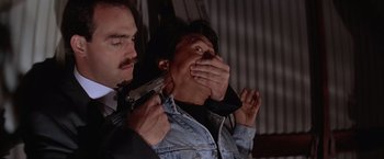 Movie still from “Rumble in the Bronx” (1995), directed by Stanley Tong – A man holding a gun over a woman's mouth; Close Up shot, Low angle