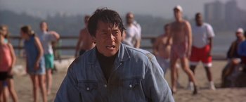 Movie still from “Rumble in the Bronx” (1995), directed by Stanley Tong – An asian man in a denim jacket is looking at the camera; Medium shot, Low angle