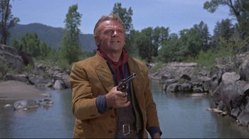 Movie still from “Run for Cover” (1955), directed by Nicholas Ray – A man holding a gun in his hand near a body of water; Medium shot, Low angle