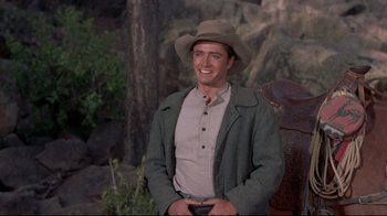 Movie still from “Run for Cover” (1955), directed by Nicholas Ray – A man wearing a cowboy hat standing next to a tree; Medium shot, Over the shoulder angle