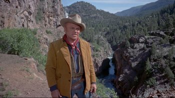 Movie still from “Run for Cover” (1955), directed by Nicholas Ray – A man wearing a cowboy hat standing in front of a river; Medium shot, Low angle