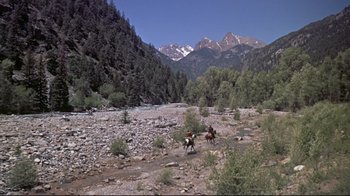 Movie still from “Run for Cover” (1955), directed by Nicholas Ray – Two people riding horses through a rocky river bed; Extreme Wide shot, High angle