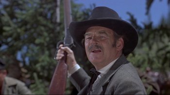 Movie still from “Run for Cover” (1955), directed by Nicholas Ray – An older man holding a rifle in a suit and hat; Close Up shot, Low angle
