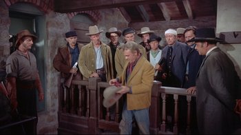 Movie still from “Run for Cover” (1955), directed by Nicholas Ray – A group of men standing around a man holding a hat; Wide shot, High angle