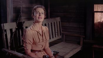 Movie still from “Run for Cover” (1955), directed by Nicholas Ray – A woman sitting on top of a wooden bench wearing glasses; Medium shot, Low angle