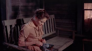 Movie still from “Run for Cover” (1955), directed by Nicholas Ray – A woman sitting on a porch swing holding a cell phone; Medium shot, High angle