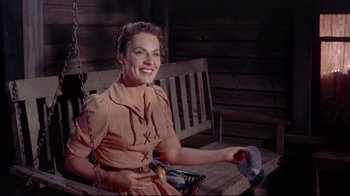 Movie still from “Run for Cover” (1955), directed by Nicholas Ray – A woman sitting on a porch swing holding a pair of scissors; Medium shot, High angle