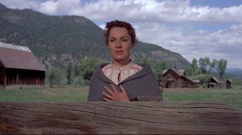 Movie still from “Run for Cover” (1955), directed by Nicholas Ray – A woman standing in front of a wooden fence with mountains in the background; Medium shot, Low angle