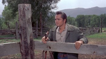 Movie still from “Run for Cover” (1955), directed by Nicholas Ray – A man holding onto a wooden fence post; Medium shot, Low angle