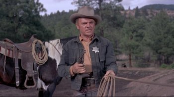 Movie still from “Run for Cover” (1955), directed by Nicholas Ray – A man holding a gun while standing next to a horse; Medium shot, Low angle