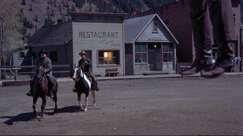 Movie still from “Run for Cover” (1955), directed by Nicholas Ray – A man riding a horse down a street; Wide shot, High angle