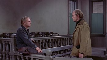Movie still from “Run for Cover” (1955), directed by Nicholas Ray – Two men are sitting in front of each other in a courtroom; Wide shot, High angle