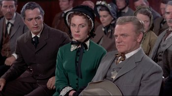 Movie still from “Run for Cover” (1955), directed by Nicholas Ray – A man and a woman sitting next to each other in front of other people; Medium shot, Over the shoulder angle
