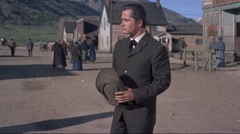 Movie still from “Run for Cover” (1955), directed by Nicholas Ray – A man in a suit and tie holding a hat; Medium shot, Low angle