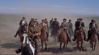 Movie still from “Run for Cover” (1955), directed by Nicholas Ray – A group of men riding horses on a dirt field; Wide shot, Low angle