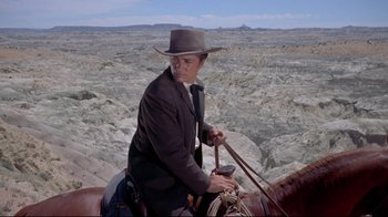 Movie still from “Run for Cover” (1955), directed by Nicholas Ray – A man riding a horse on top of a mountain; Wide shot, Low angle