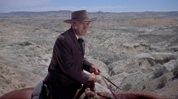 Movie still from “Run for Cover” (1955), directed by Nicholas Ray – A man riding a horse on a mountain top; Wide shot, Low angle