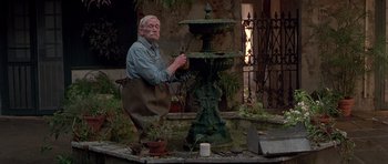 Movie still from “Runaway Jury” (2003), directed by Gary Fleder – An old man in an apron working on a fountain; Wide shot, Low angle