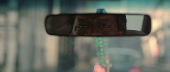 Movie still from “Runaway Jury” (2003), directed by Gary Fleder – The reflection of a man in the rear view mirror of a car; Extreme Close Up shot, Over the shoulder angle