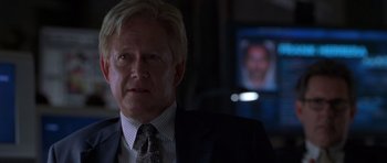 Movie still from “Runaway Jury” (2003), directed by Gary Fleder – A man in a suit and tie in front of a television; Close Up shot, Over the shoulder angle