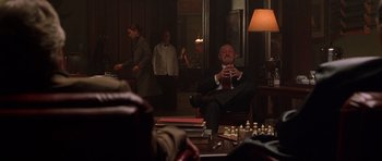 Movie still from “Runaway Jury” (2003), directed by Gary Fleder – A man sitting in a chair in front of a chess board; Wide shot, Over the shoulder angle