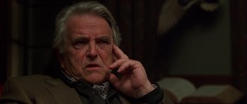 Movie still from “Runaway Jury” (2003), directed by Gary Fleder – An older man is sitting in a chair with his hand to his face; Close Up shot, Over the shoulder angle